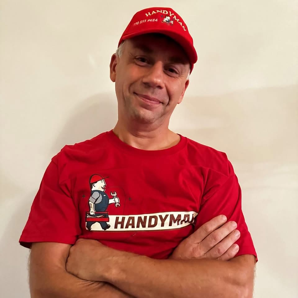 Ivan, owner of I&I Home Repair, smiling with arms crossed in a red handyman cap and shirt